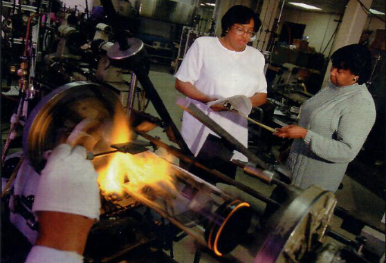 VitroTech artisans working together at the glass lathe with vibrant flames